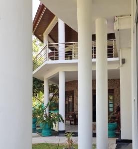 Blick auf die Außenseite eines Gebäudes mit Säulen in der Unterkunft White Win Villa in Elewala