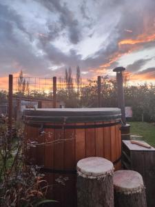 a hot tub in a yard with a sunset in the background at Cabin with hottub at homestay in Karitane