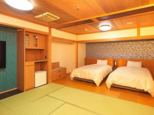 a bedroom with two beds and a tv in it at Kichimu in Kamogawa