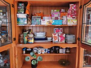 a pantry with plates and dishes on shelves at Cabin with hottub at homestay in Karitane