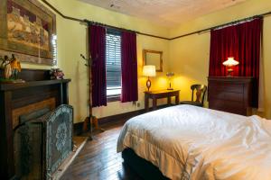 サバンナにある5 BR Downtown Savannah GAのベッドルーム1室(ベッド1台、暖炉、赤いカーテン付)