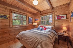 a bedroom with a bed in a log cabin at Cozy Pet-Friendly Cabin w Private Hot Tub Fenced In Yard Walk to HOA Beach & Pier in Homewood