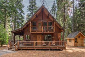 a log cabin with two dogs sitting on the decks at Cozy Pet-Friendly Cabin w Private Hot Tub Fenced In Yard Walk to HOA Beach & Pier in Homewood