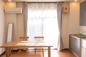 eine Küche mit einem Tisch und Stühlen vor einem Fenster in der Unterkunft 富江宿 in Tomie