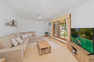 a living room with a couch and a flat screen tv at Dejablu- 8 Cook Drive SWR in South West Rocks
