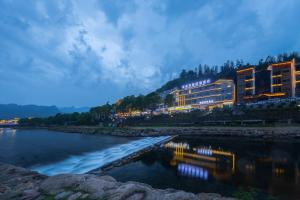 budynek na brzegu rzeki w nocy w obiekcie Sochi Smart Resort Zhangjiajie w mieście Zhangjiajie
