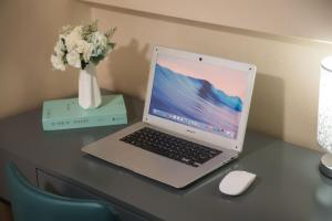 a laptop computer sitting on a desk with a vase of flowers at Zun Xiang Executive Apartment - Shenzhen Futian Exhibition Center in Shenzhen