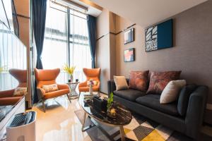 a living room with a black couch and orange chairs at Zun Xiang Executive Apartment - Shenzhen Futian Exhibition Center in Shenzhen