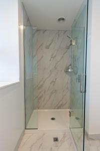a shower with a glass door and a tile floor at Glamorous 2 bed CBD townhouse w/King bed in Christchurch