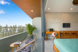 Zimmer mit einem Balkon, einem Bett und einem Schreibtisch. in der Unterkunft Bon Sand Villa & Spa Hoi An in Hoi An