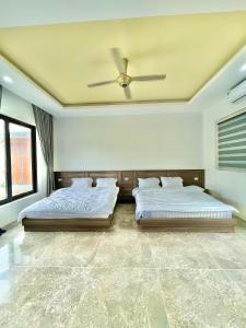 two beds in a bedroom with a ceiling fan at AKIRA VILLA _ Venuestay in Ba Vì