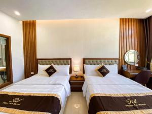 ハロンにあるAn Hotel Ha Longのベッド2台と鏡が備わるホテルルームです。