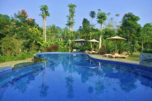 a large blue swimming pool with trees and umbrellas at Sarga Earthing Resort in Cianjur