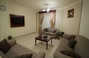 ein Wohnzimmer mit zwei Sofas und einem Fernseher in der Unterkunft سيزن للوحدات السكنية in Dschidda