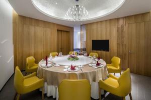 Jinshanling Great Wall Hotel في تشنغده: قاعة اجتماعات مع طاولة وكراسي صفراء
