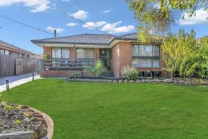 una casa con un césped verde delante de ella en House near Melbourne Airport en Melbourne