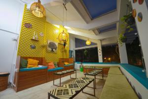a living room with a yellow wall with a blue couch at House of Stories - Indiranagar, Bangalore in Bengaluru