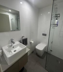 een witte badkamer met een wastafel en een toilet bij Drummoyne Apartment in Sydney