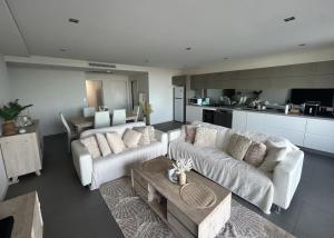 sala de estar con 2 sofás blancos y cocina en Drummoyne Apartment, en Sídney