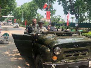 two men sitting in the back of an army truck at Tam Coc Scenery Homestay in Văn Lâm