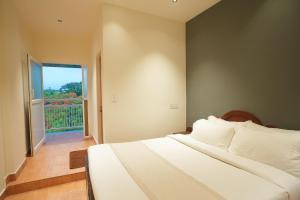 a bedroom with a white bed and a balcony at Rasha residency in Kalpetta