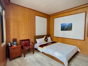 um pequeno quarto com uma cama e uma cadeira em Thái Thịnh Hotel em Dong Van
