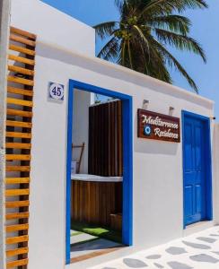 a building with a blue door and a palm tree at Meditarranee Residence in Camocim