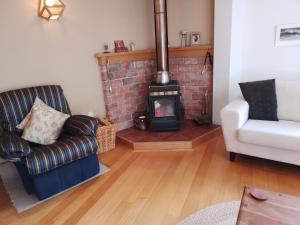 a living room with a fireplace and a couch and a chair at Birds Eyes Te Awanga in Te Awanga