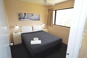 a hotel room with a bed with a white towel on it at Riverview Holiday Apartment 65 - Kalbarri WA in Kalbarri