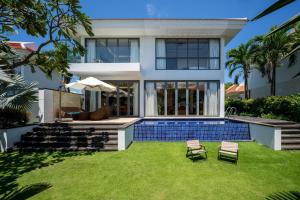 a house with a swimming pool and a lawn at Ocean Beach Resort Da Nang in Danang