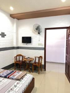 Schlafzimmer mit einem Bett, einem Tisch und einem TV in der Unterkunft KHÁCH SẠN HOÀNG TRÍ 89 (HOANG TRI 89 HOTEL) in Hố Nai