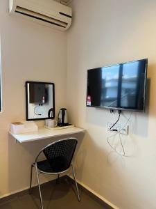a desk with a chair and a large television on a wall at Jb Sojourn in Skudai