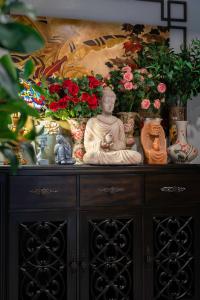 a statue on top of a cabinet with vases and flowers at Aaron Boutique Hotel in Nha Trang