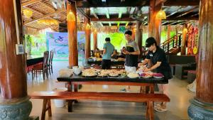 Un groupe de personnes autour d'une table avec de la nourriture dans l'établissement Mạ Homestay riverside, à Thanh Hóa