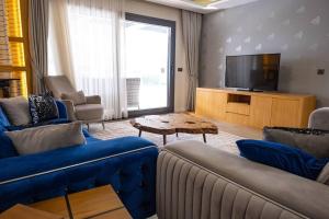 a living room with blue couches and a television at Havuzlu lüks yeni 4 oda in Cesme