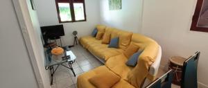 a living room with a yellow couch with blue pillows at villa gracieuse in Corps de Garde