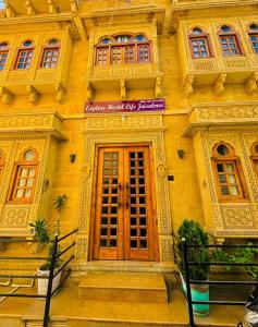 a yellow building with a wooden door and windows at Explore Hostel Life Jaisalmer in Jaisalmer