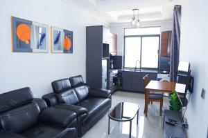 ein Wohnzimmer mit schwarzem Ledersofa und eine Küche in der Unterkunft CosyNook in Kigali