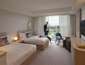 une chambre d'hôtel avec deux lits et un homme et une femme dans l'établissement RACV Royal Pines Resort Gold Coast, à Gold Coast