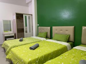 2 camas en una habitación con paredes verdes en ควีนเพลส สระบุรี Queenplace Saraburi, en Saraburi