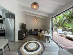 a living room with a couch and a kitchen at Tui Cottage - Waiheke Escapes in Onetangi