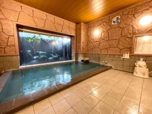 una piscina en una habitación con una pared de piedra en Hotel Route-Inn Yuki, en Yuki