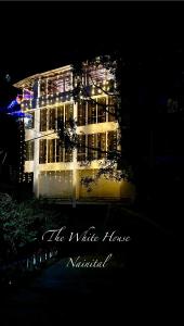 un gran edificio con luces encendidas por la noche en The White House en Nainital