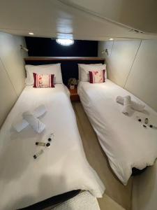 two beds in a small room with towels and shoes at Motor Boat Accommodation in Torquay