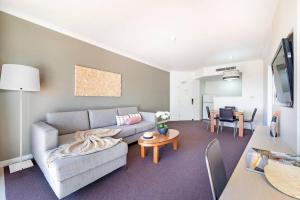 un soggiorno con divano e tavolo di 'Towering Palms' Resort-style Stay with a Separate Studio a Darwin