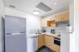 una cucina con armadi in legno e frigorifero bianco di 'Towering Palms' Resort-style Stay with a Separate Studio a Darwin