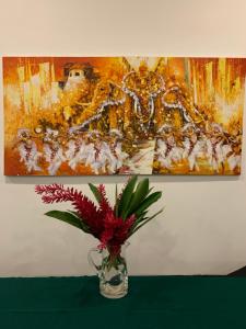 un vase avec des fleurs sur une table devant un tableau dans l'établissement Anveela, à Beruwala