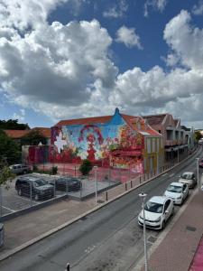 um mural na lateral de um edifício com carros estacionados em THE VIEW APPARTMENTS em Willemstad
