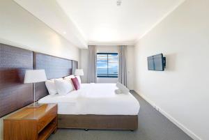 ein Schlafzimmer mit einem großen weißen Bett und einem Fernseher in der Unterkunft Sundrenched and Scenic with Sprawling Water Views in Darwin