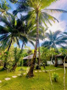 a group of palm trees in front of a house at El Nido Coco Resort in El Nido